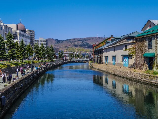 The Otaru canal in spring, stone warehouses along one bank and a walkway along the other